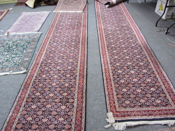 A pair of Indian runners of Fereghan design, the indigo fields each with a herate design, madder vine border, 490cm x 82cm. (2)