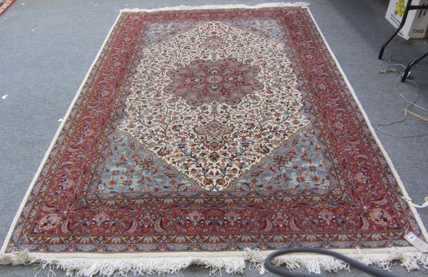 An Indian carpet, the ivory field with a madder rosette medallion, pale indigo spandrels, all with floral sprays, a complementary madder border, 282cm
