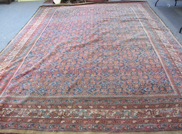 A Fereghan carpet, Persian, the indigo field with an allover madder herate design, an ivory waved vine and leaf border, 404cm x 310cm.