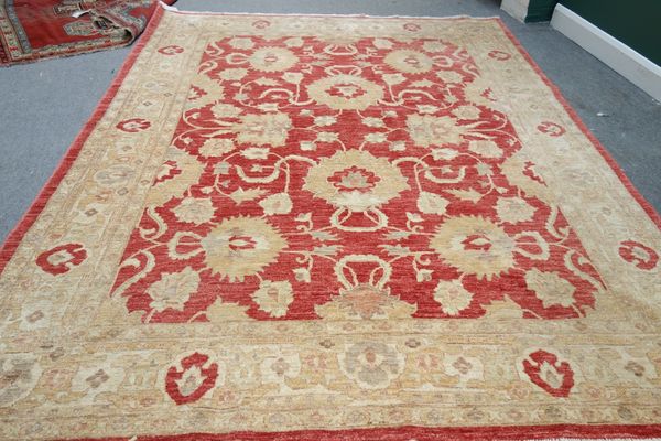 A Turkish carpet, the madder field with a bold palmette and vine design, a complementary beige palmette border, 300cm x 240cm.