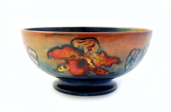 A Moorcroft pottery bowl, circa 1940, decorated with orchids and summer flowers against a mottled blue and red ground, with impressed and painted mark