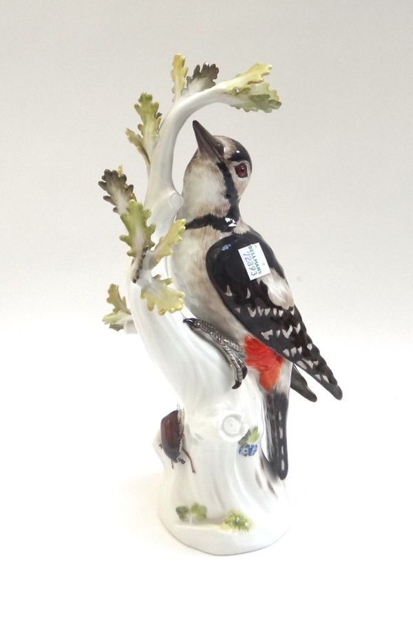 A Meissen porcelain great spotted woodpecker, early 20th century, modelled on a leafy branch, with blue crossed swords mark, incised 3086 (a.f), 28cm