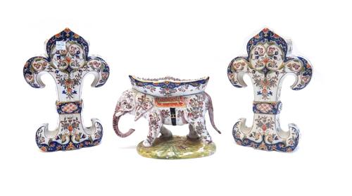 A French faience 'elephant' vase, early 20th century, 15cm high, and a pair of faience 'fleur de lys' shaped vase garnitures, 25cm high. (3)