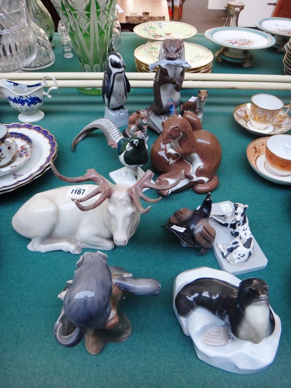 A collection of Heubach porcelain animals, comprising; a stag, 24cm wide, a pheasant, two other game birds, a racoon group, a penguin, a seal by M. Bo