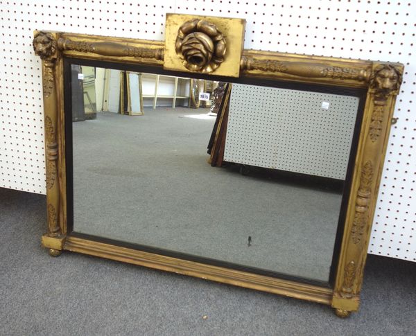 A 19th century gilt framed rectangular wall mirror, with floral carved crest above the rectangular mirror plate, the frame with scale moulded turned c