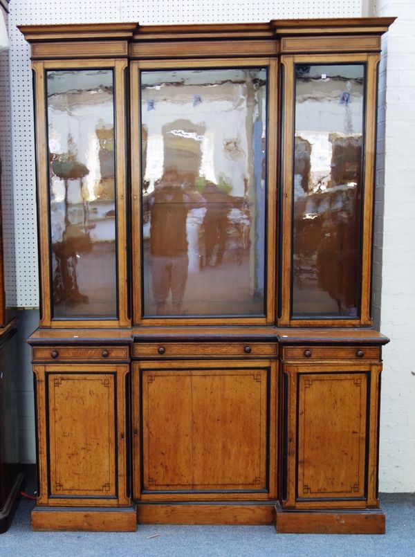 A 19th century oak and ebonised inverted breakfront bookcase cupboard, with three glazed doors over three drawers and three further panelled cupboards