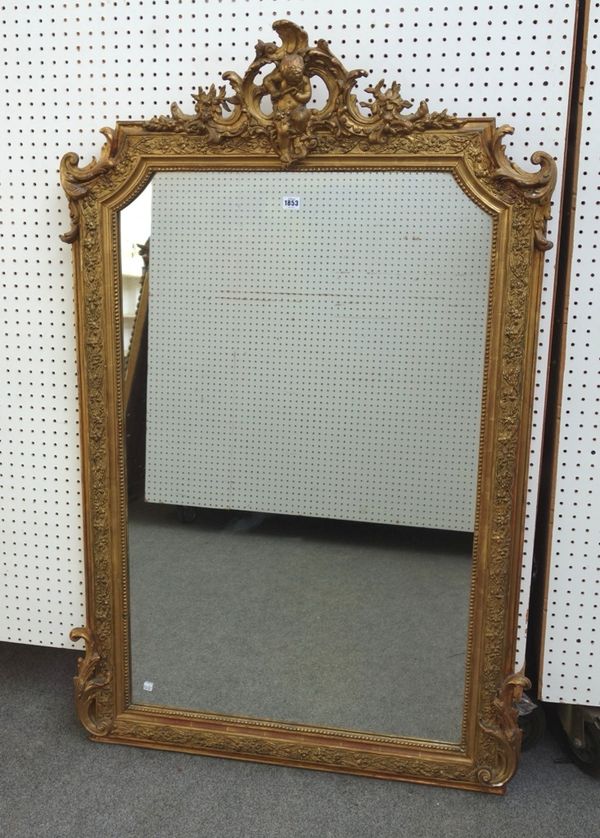 A late 19th century gilt framed overmantel mirror, the opposing 'C' scroll crest centred by a cherub playing a flute, above a floral moulded frame mou