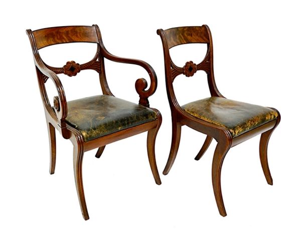 A set of twelve George IV mahogany framed dining chairs, the carved waist rail centred by a compressed Tudor Rose, over straight front seat on sabre s