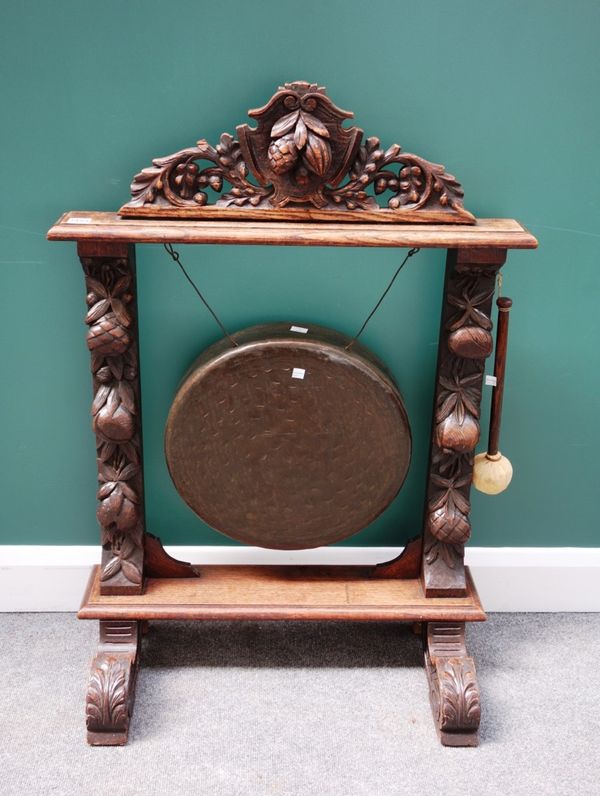 A Victorian oak framed dinner gong with carved fruiting frame on four scroll supports, 71cm wide.