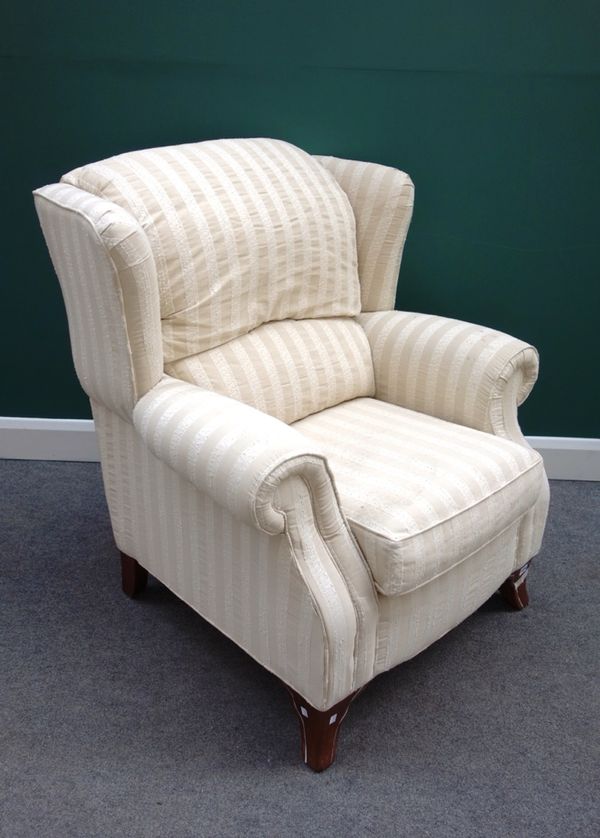A generously proportioned wing back easy armchair, on splayed stained beech supports.