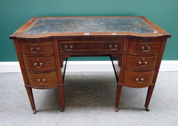 An Edwardian inlaid mahogany double bowfront writing desk, with seven drawers about the knee, on tapering square supports, 109cm wide.