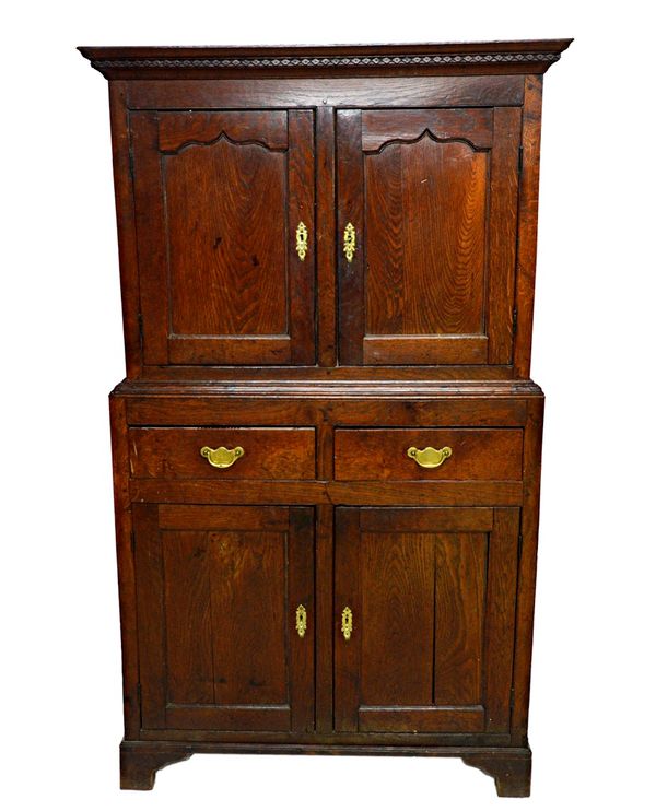 An 18th century oak side cupboard, the diamond carved cornice over a pair of shaped panel doors, two short drawers and a further pair of cupboards, on