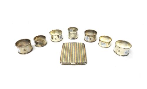 Silver, comprising; a rectangular cigarette case, the exterior with two colour gilt and engine turned banded decoration, London 1921, a set of four na