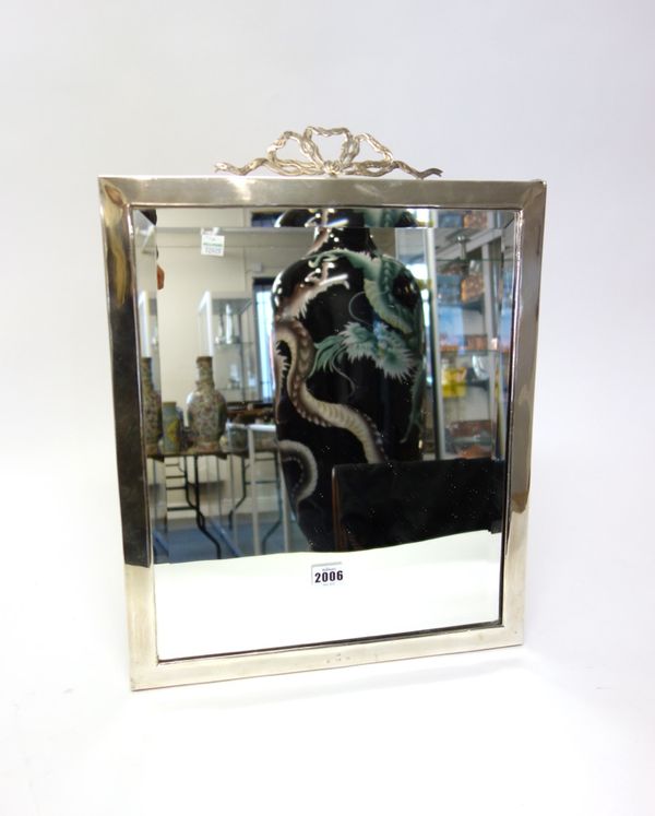 A silver framed large rectangular strut backed mirror, the top with a bow surmount, having engraved decoration, fitted with a bevelled glass, size of