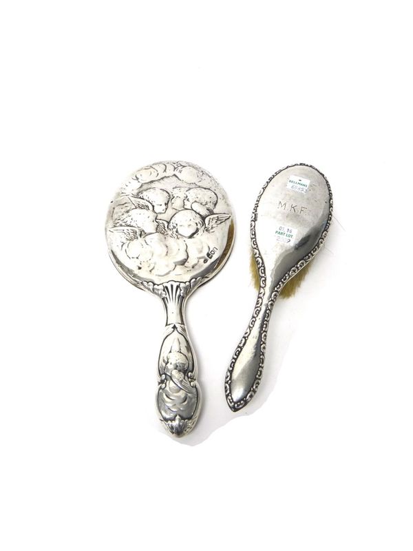A late Victorian lady's silver mounted oval hand mirror, embossed with cherub's faces, London 1897 and a silver mounted hairbrush, having a scroll dec