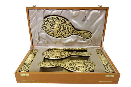 A six piece silver gilt mounted lady's dressing table set, comprising; a hand mirror, two hairbrushes, two clothes brushes and a comb, the Victorian m