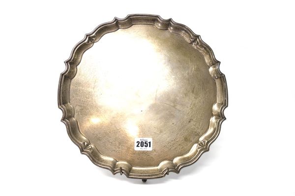 A silver shaped circular salver, having a pie-crust rim, in the Chippendale style, raised on four pad feet, presentation inscribed To Alexander Freder