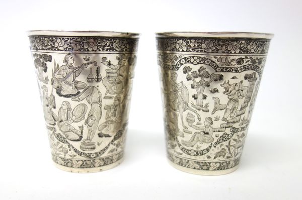 A pair of Eastern beakers, each of tapering cylindrical form decorated with figures, birds, trees and floral motifs. within floral and foliate borders