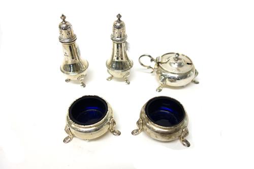 Silver condiments, comprising; a mustard pot, of circular form, raised on three feet, London 1969, with a plated spoon, a pair of circular salts, each
