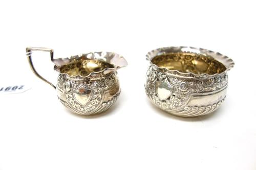 A silver milk jug, with semi spiral fluted and floral embossed decoration and with a shaped rim, London 1901 and a sugar bowl, in a similar matching d