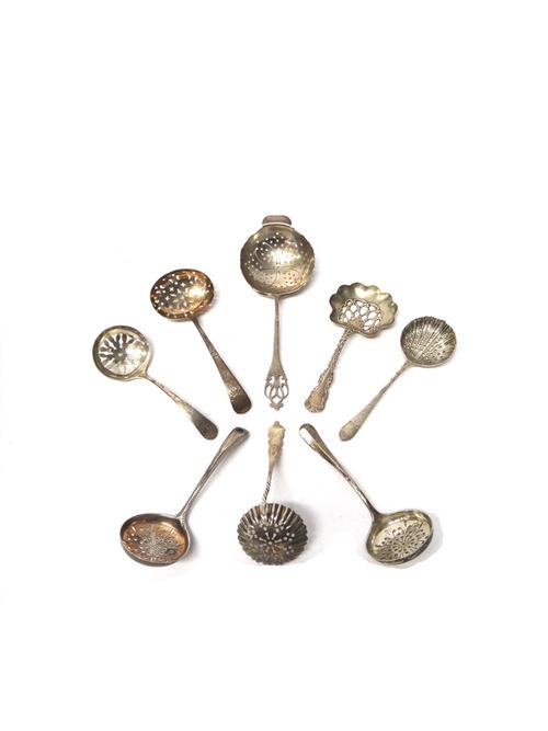 A silver tea strainer, the handle with pierced decoration, Sheffield 1929, six silver sugar sifting spoons and a sterling sugar sifting spoon, various