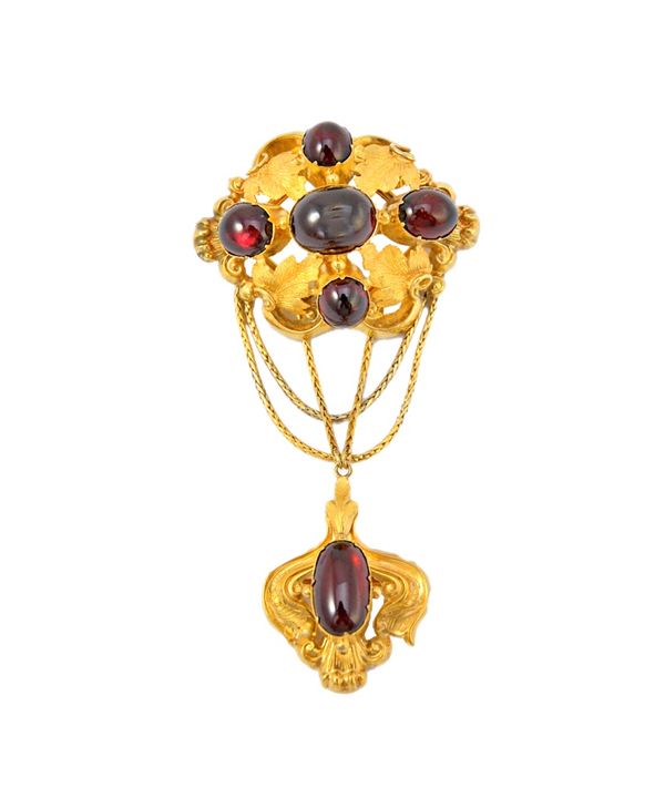 A Victorian gold and cabochon garnet set brooch in a leaf and scroll setting, with a cabochon garnet set drop, 4.2cm wide, gross weight 16gms, in a fi