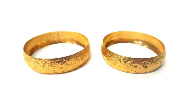 Two Middle Eastern gold bangles, each of circular form, with engraved decoration, indistinctly marked 18, combined weight 31.5 gms.