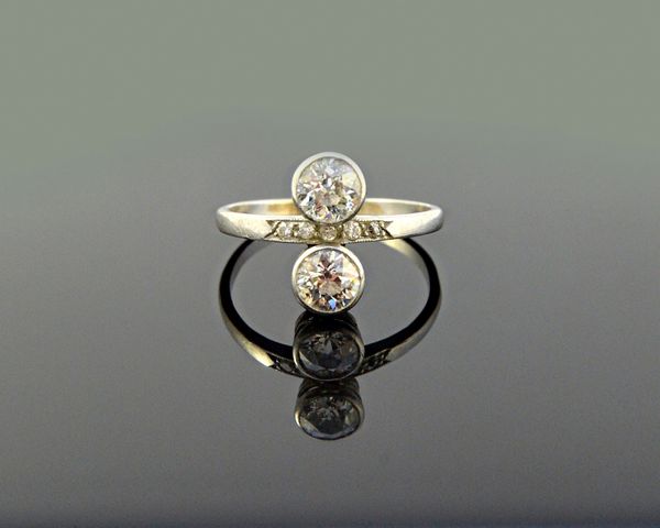 A diamond ring, collet set with the two principal cushion shaped diamonds in an over and under design and with a row of five small cushion shaped diam