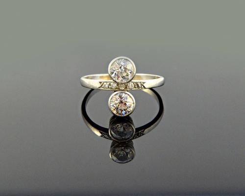 A diamond ring, collet set with the two principal cushion shaped diamonds in an over and under design and with a row of five small cushion shaped diam