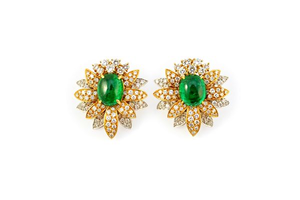 A pair of two colour gold, cabochon emerald and diamond set earclips, each designed as a stylized flowerhead, claw set with an oval cabochon emerald a