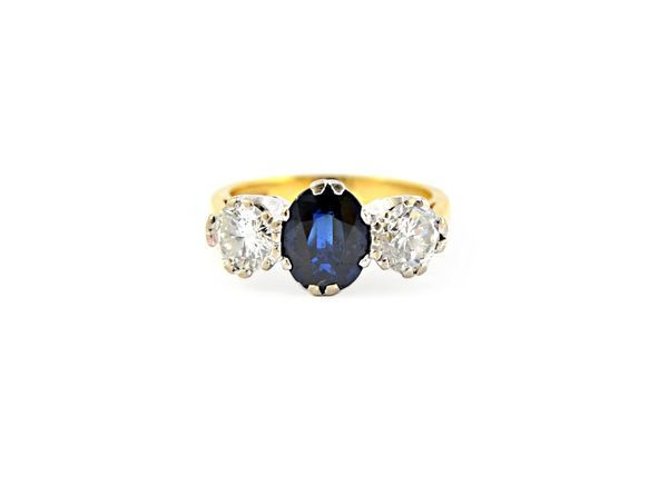 An 18ct gold, sapphire and diamond set three stone ring, claw set with the oval cut sapphire at the centre, approx 1.54 cts, between two circular cut