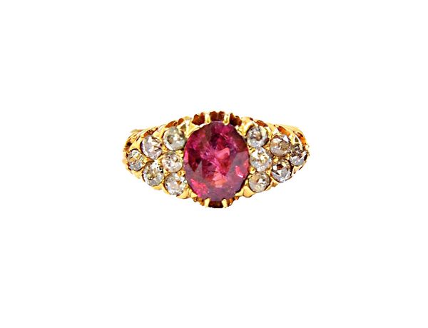 A gold, ruby and diamond set ring, claw set with the oval cut ruby at the centre, between diamond set six stone shoulders, mounted with cushion shaped