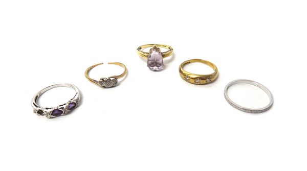 A platinum decorated wedding ring, a gold and diamond set three stone ring, in a crossover design and three further 9ct gold and gem set rings.