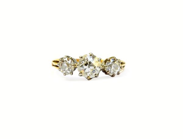 A gold and diamond set three stone ring, claw set with a row of cushion shaped diamonds and with the principal diamond mounted at the centre, detailed