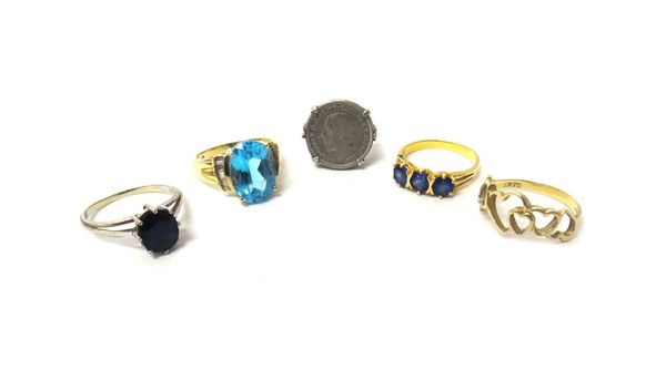 A gold and blue gem set three stone ring, a 9ct gold ring, pierced in a heart shaped design, a 9ct gold ring, claw set with an oval cut blue topaz, be