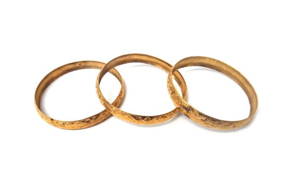 Three gold circular bangles, each having engraved decoration and detailed 18 K, combined weight 39 gms.