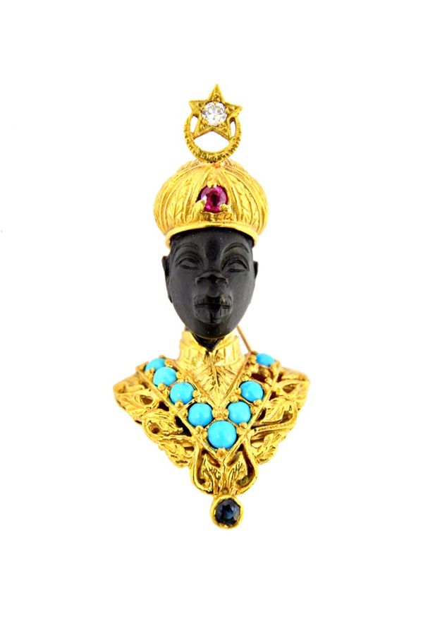 An 18ct gold, diamond, ruby, sapphire and turquoise set brooch, designed as the bust of a Blackamoor wearing ceremonial attire (one turquoise lacking)