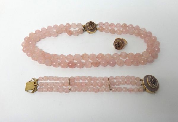 A two row necklace of rose quartz beads on a 9ct gold and carbuncle garnet set oval clasp, a three row bracelet of rose quartz beads on a matching cla