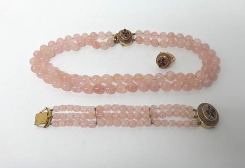 A two row necklace of rose quartz beads on a 9ct gold and carbuncle garnet set oval clasp, a three row bracelet of rose quartz beads on a matching cla