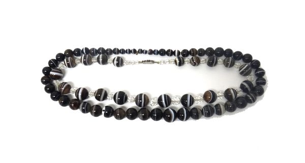 A single row necklace of graduated banded agate beads and a single row necklace of graduated banded agate beads, spaced with facet cut colourless past