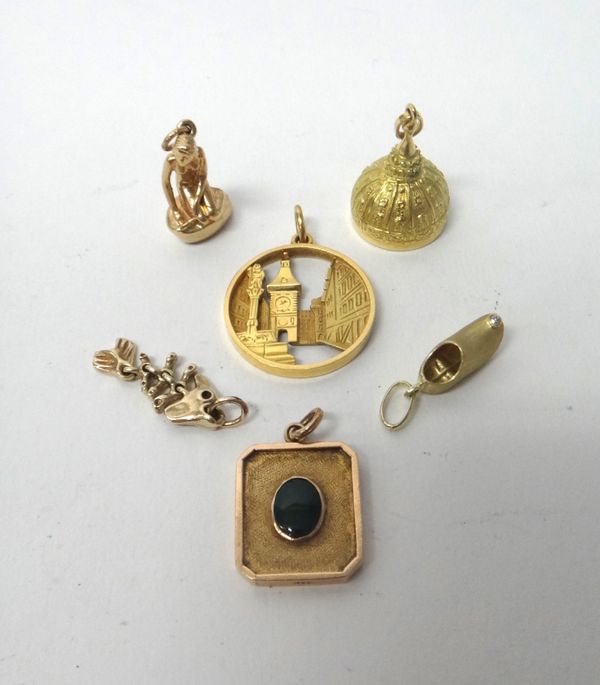 A gold pendant, pierced with a clock tower scene, detailed 750 Swiss, a gold charm designed as a clog, detailed 585, a gold pendant formed as a bell,