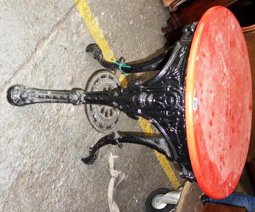 A 19th century pub table, with red painted circular top over a black painted cast iron base.