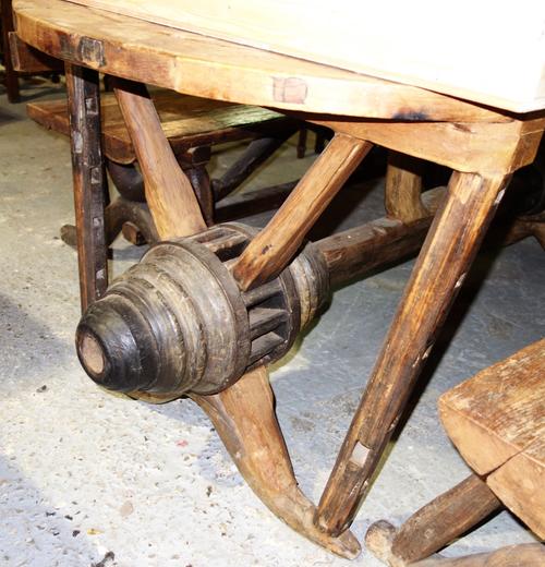 A teak framed dining table on reclaimed cart wheel base.