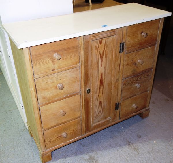 A pine side cabinet with eight short drawers and a cupboard.