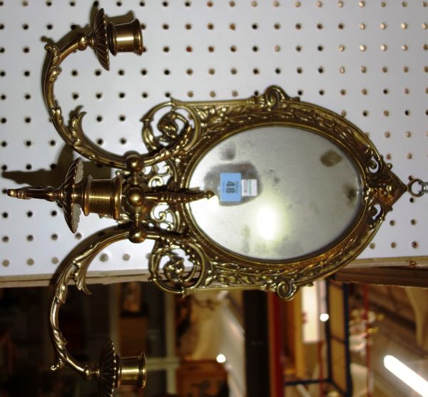 A gilt brass oval wall mirror with sconces.