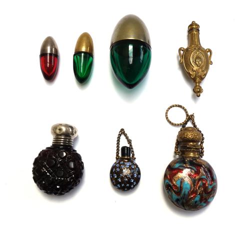 Three coloured glass and metal mounted scent bottles, early 20th century, of egg form, the largest 6.5cm, together with a gilt and coloured glass 'moo