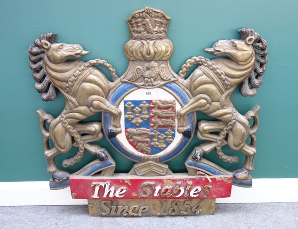 A wood and sheet metal mounted coat of arms titled 'The Stables Since 1854' with painted decoration, 103cm high.