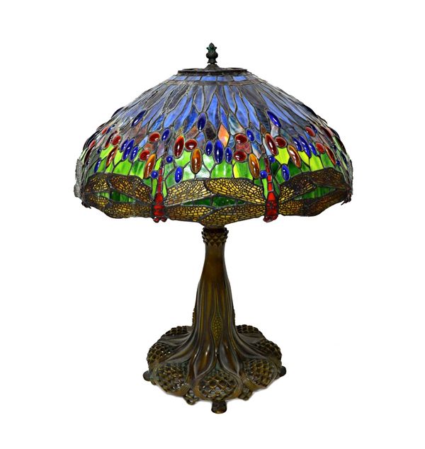 A bronze and coloured glass Tiffany style table lamp, late 20th century, with a dragonfly shade over a body cast with pierced foliate Art Nouveau deco