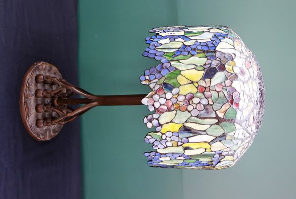 A bronze and coloured glass Tiffany style table lamp, late 20th century, with a foliate coloured shade over a naturalistic bronze body and circular ba