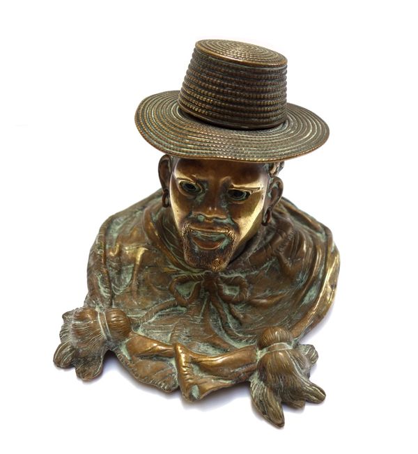 A Victorian brass novelty inkwell modelled and cast as the head of a Nubian male, his hat opening to reveal an ink recess, on a shaped base, 9cm high,
